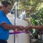 Clinical Director Cesar Santos helps cut the ribbon on the first water tank installed.